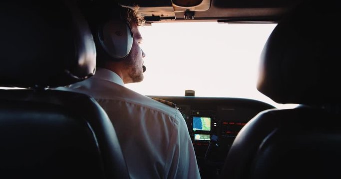 Handsome pilot flying airplane in cockpit. Sunrise aerial view of morning flight in small plane