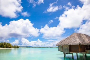 Luxury thatched roof honeymoon bungalow in a vacation resort in the blue lagoon of the Pacific island of Bora Bora, near Tahiti, in French Polynesia.  Villa over water.