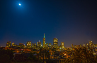 Fototapeta premium San Francisco cityscape and a full moon at night, taken from Coit Tower. Downtown and the financial district