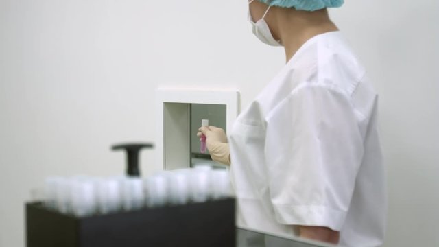 Ivf follicular puncture, female assistant doctor hold test tube with oocyte retrieved, nurse pass plastic vial with pink media liquid, egg retrieval procedure.