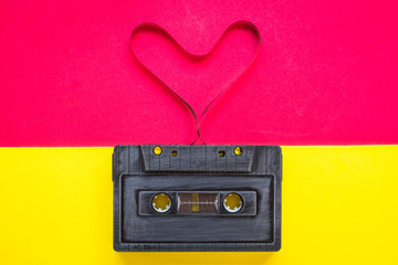 heart shape from cassette tape over paper background, top view