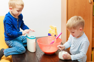Two kid boys cooking, making cake in bowl