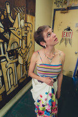 Young caucasian woman dressed in colorful bohemian style in a grungy, urban location featuring graffiti
