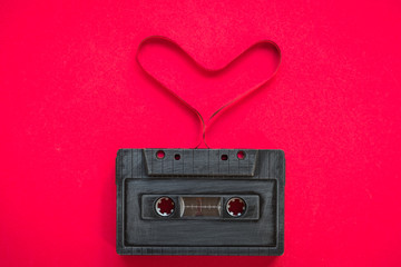 heart shape from cassette tape over paper background, top view