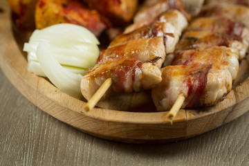 Bacon wrapped chicken breast skewers - tasty meat special shot close up with some onions on the side