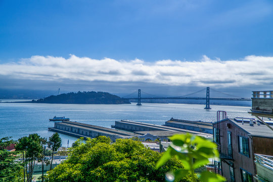 Bay brudge in San Francisco in the early morning with fog and clouds lingering near by.