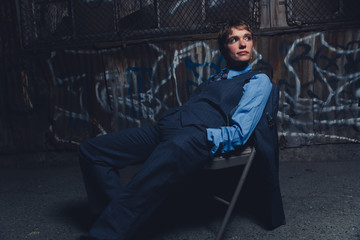 Young androgynous woman dressed in mens clothing in a grungy, urban outdoor location