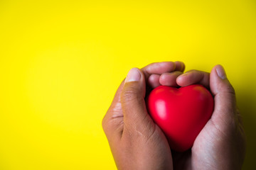 Fototapeta premium man hands giving red heart on yellow background