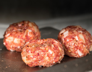 Minced meatballs with onions, bacon bits and spicy seasoning, shot close up
