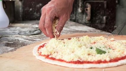 Cheese being spread on tomato sauce on pizza base. Selective foc