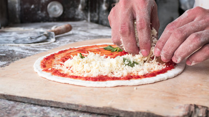 Cheese being spread on tomato sauce on pizza base. Selective foc