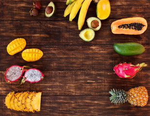 Tropical fruit on dark wooden background, top view
