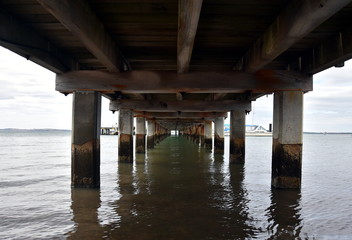 Under the wooden Pier at Rhyll (Philip Island, Victoria, Australia). Infinity view under the pier of weathered pilings.
