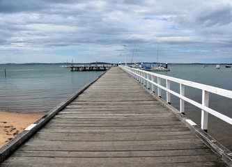 Fototapeta na wymiar Old wood bridge pier at Rhyll (Philip Island, Victoria, Australia). Old wooden jetty with natural background.