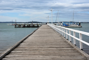 Fototapeta na wymiar Rhyll, Australia - December 29, 2016. Old wood bridge pier at Rhyll (Philip Island, Victoria, Australia). Old wooden jetty with natural background.