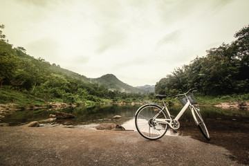 Fototapeta premium Bicycle on the bridge cross over river : Khiriwong Fuit Village ,Nakhon Si Thammarat Thailand (disappointed holiday concept ; vintage style) 