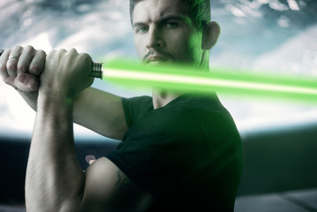 A young man with a laser sword on the background of cosmic scenery,