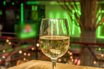 Glass of white wine on blurred lights background