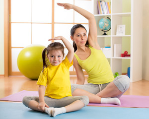 Portrait of kid and mother doing physical exercise at home