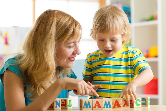 Mother teaches son child to read letters and words playing with cubes