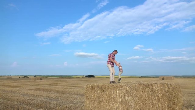 Father and son in the field. Little boy jumps on the hay in slowmo.