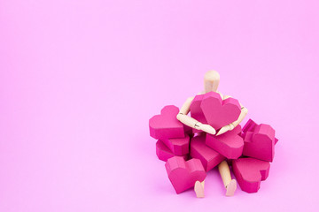 Wooden dummy holding paper box red heart shape on pink backgroun