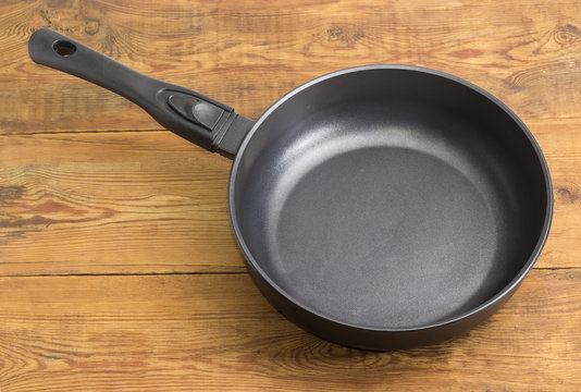 Frying pan with ceramic non-stick coating on wooden surface