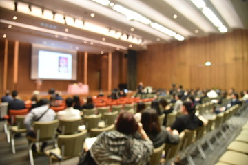 Obraz premium Blurred image of education people and business people sitting in conference room for profession seminar and the speaker is presenting new technology and idea sharing with the content activity.