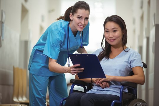 Portrait of female nurse assisting patient over clipboard