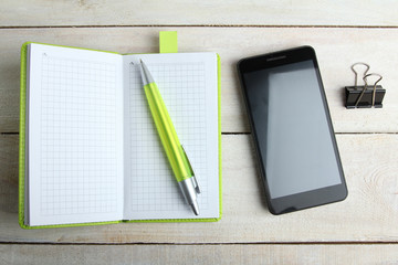 Phone, pen, notebook, paper clip on office desk in color green Pantone 2017