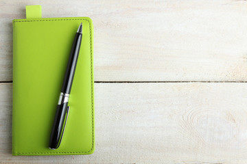 Notebook, pen on a wooden background in color green Pantone 2017