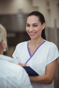 Female nurse interacting with patient in corridor