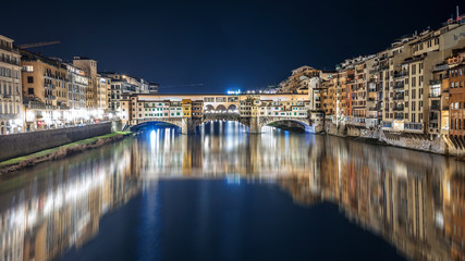 Ponte Vecchio at night is reflected in the Arno river in Florence, Italy
