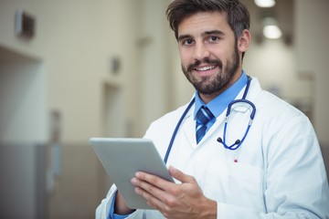 Portrait of male doctor using digital tablet in corridor