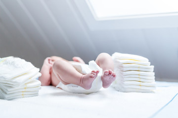 Feet of newborn baby on changing table with diapers