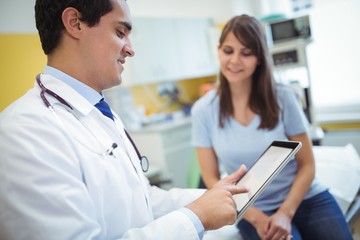 Doctor using digital tablet while consulting patient