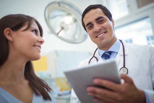 Portrait of doctor using digital tablet while consulting patient
