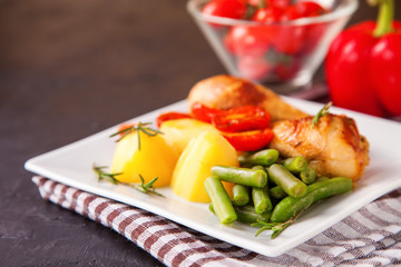 the baked chicken legs with vegetables in a plate on a table, selective focus, copy space