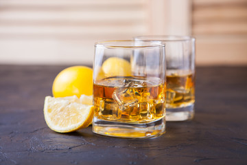 whisky with ice and a lemon in a glass against a dark background, selective focus, copy space