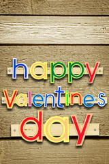 Nailed greeting text Happy Valentines day on brown wooden background