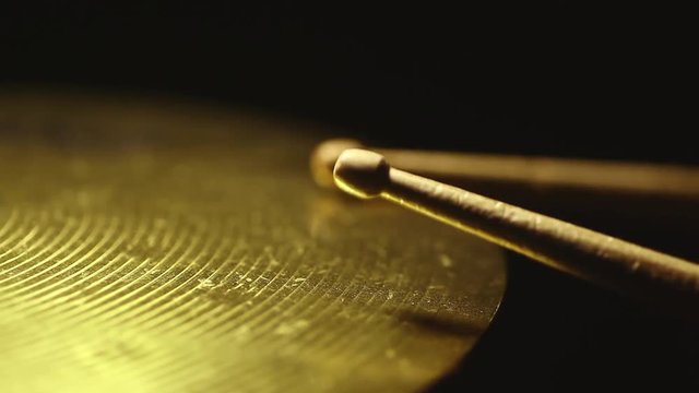Close up footage of two drum sticks hitting a cymbal.