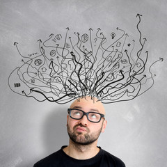 Young attractive perplexed geek man with brainstormaing arrow ov