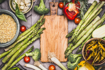 Vegetarian ingredients for pearl barley porridge or salad around wooden cutting board, top view.  Healthy clean food or diet nutrition concept