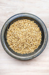 Pearl barley in bowl on white wooden background, top view#