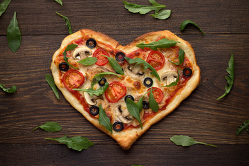 Tasty italian heart shaped pizza with chicken, mushrooms and scattered arugula's leaves on wooden rustic background. - 133489312