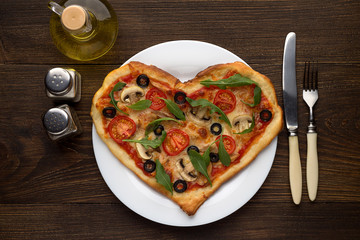 Idea of romantic dish on Valentine's day: heart shaped pizza with mushrooms and chicken on wooden background.