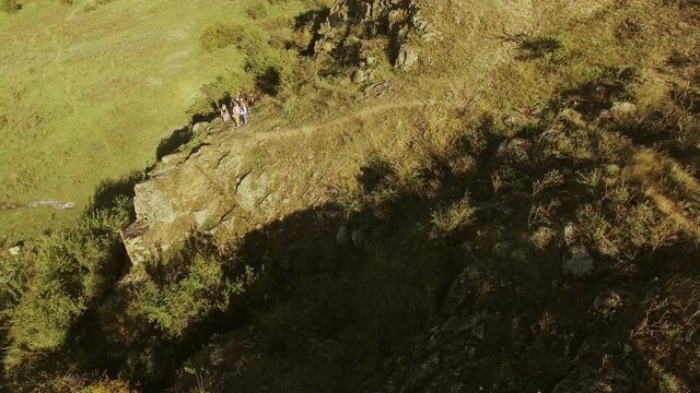 Panoramic drone view with group of tourists walking through rocky prairie. Flyover