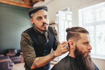 Bearded man getting haircut by barber