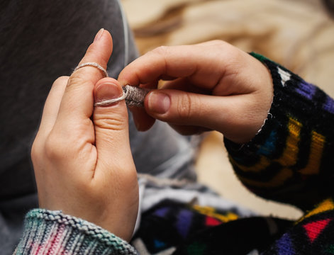 close up of woman hands knitting with needles and grey yarn