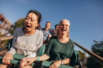 Foto op Aluminium Amusementspark Vrienden juichen en rijden achtbaan in pretpark
